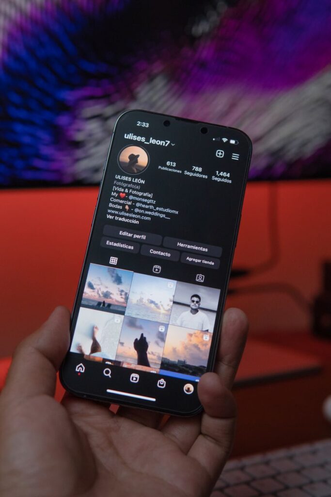 Close-up of a smartphone displaying a social media profile in a warm indoor setting.